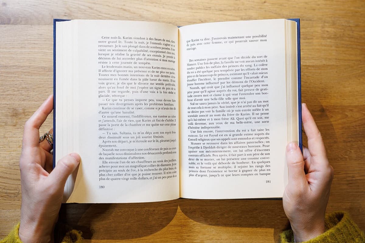 Unas manos sujetan un libro abierto sobre una mesa de madera